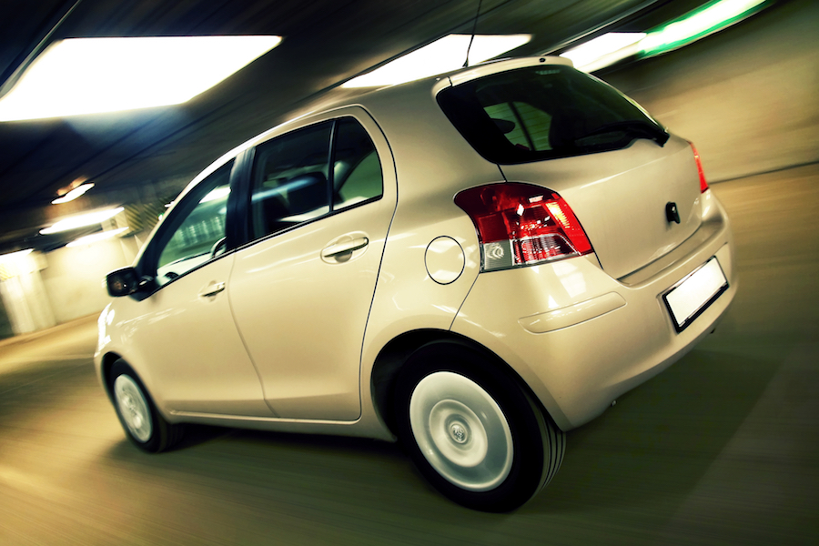 Rear view of compact hatchback driving fast in parking house